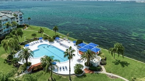 A resort with a large swimming pool, palm trees, and a view of the ocean. - Paradise Penthouse (St. Petersburg)