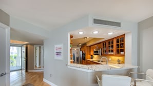 A modern kitchen with wooden cabinets, a built-in microwave, and a white countertop. - Paradise Penthouse (St. Petersburg)