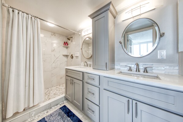 Een moderne badkamer met een douche, een wastafel en een spiegel.