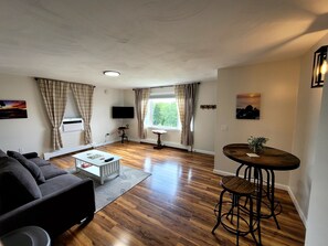 A living room with a sofa, coffee table, and a TV mounted on the wall. - Perfectly Centered in the Birch Harbor Village! (Birch Harbor)
