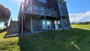 Une maison en bois à deux étages, dotée d’un balcon, d’un escalier et du numéro « 5 » sur la porte.