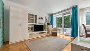 A modern living room with a TV, sofa, and a dining area with a table and chairs.
