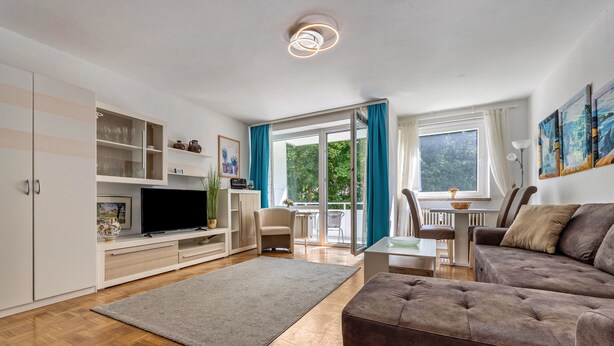 A modern living room with a flat-screen TV, sofa, and dining area.