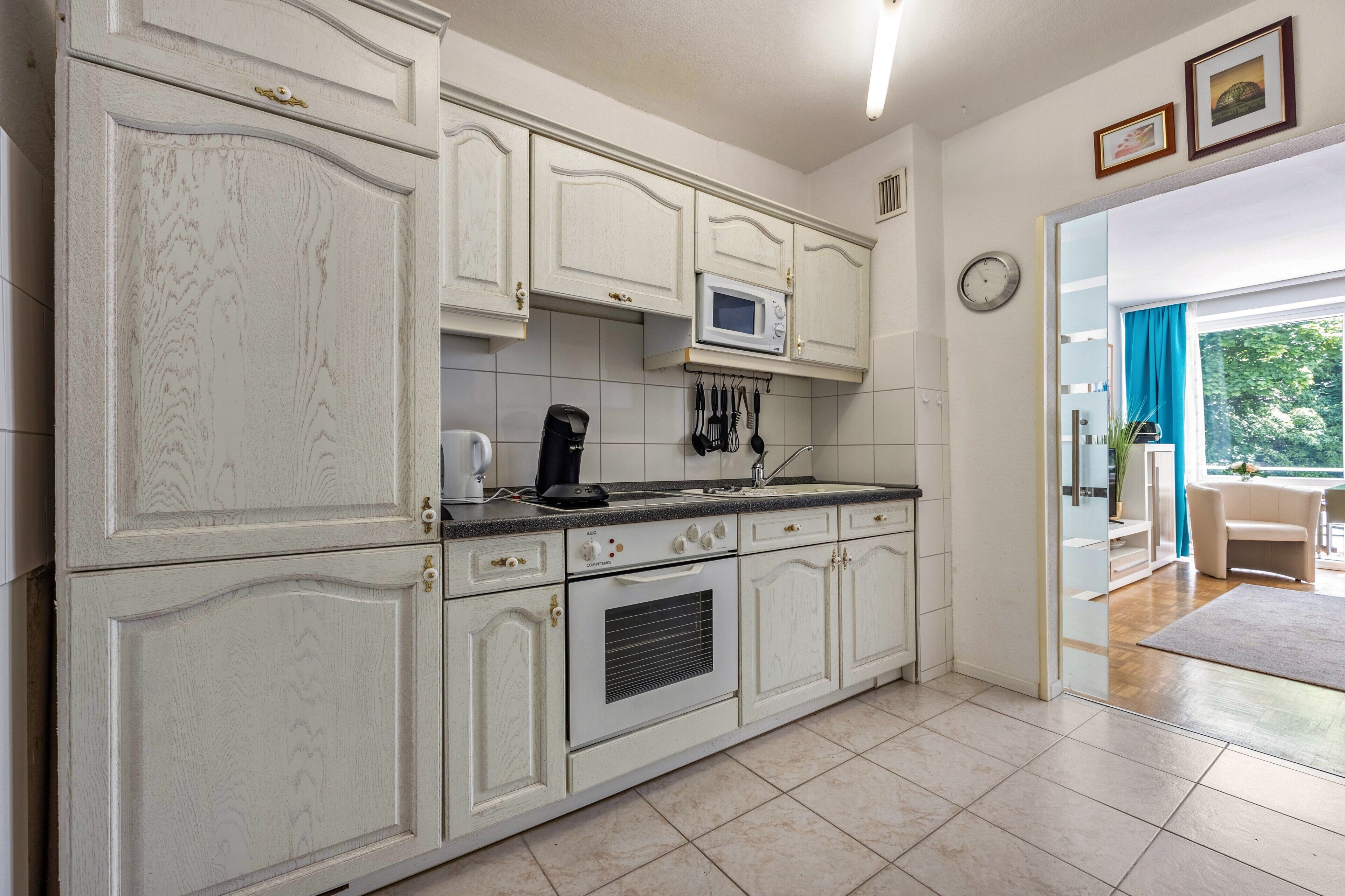 A kitchen with white cabinetry, a microwave, and a coffee maker.