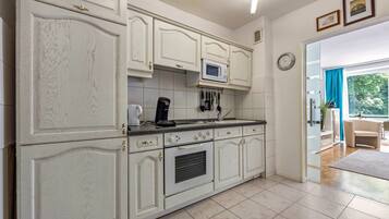 A kitchen with white cabinetry, a microwave, and a coffee maker.