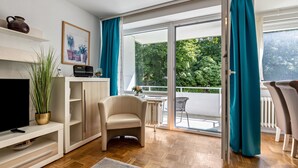 A modern living room with a TV, sofa, and a balcony with curtains.