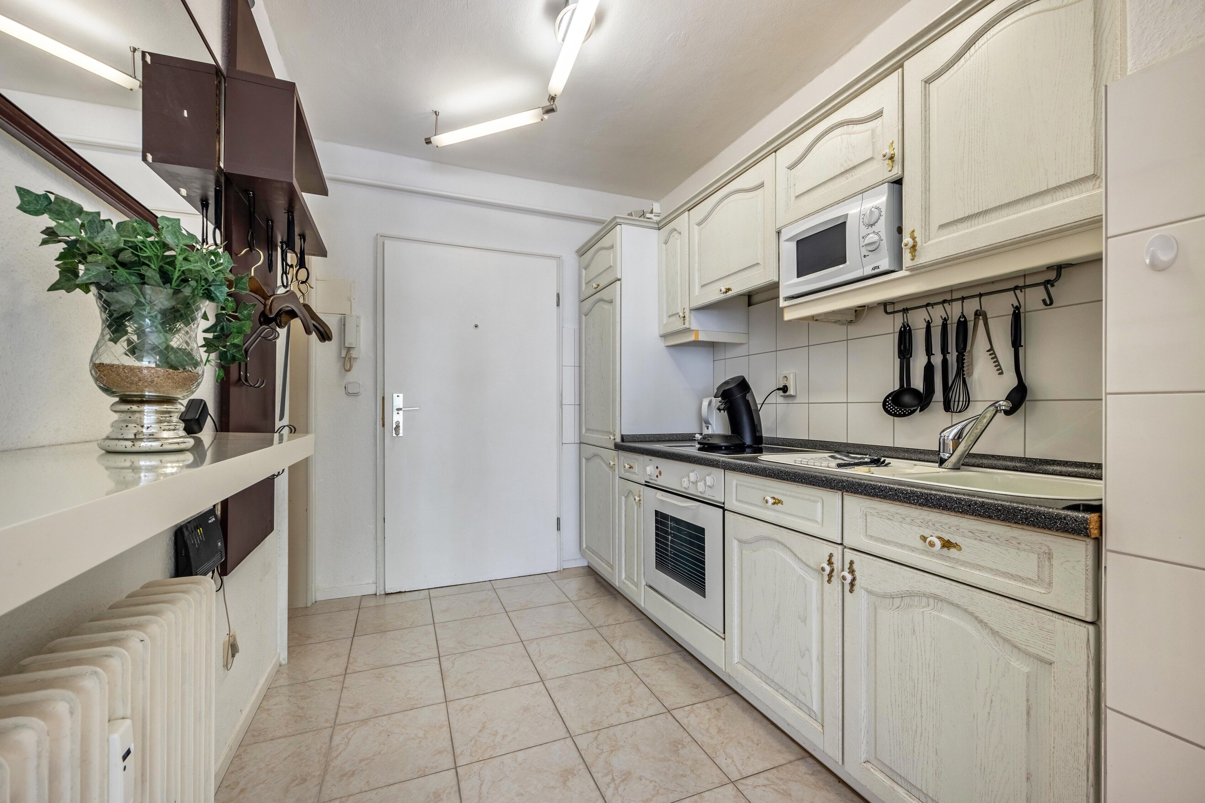 Cocina con armarios blancos, microondas y hervidor.