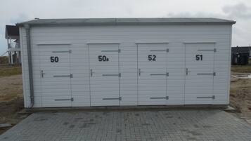 Een gebouw met genummerde deuren, een verharde ingang en een bewolkte lucht.
