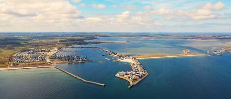 Vista aérea de una zona costera con un puerto deportivo, un muelle y una pequeña isla con edificios.