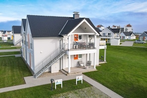 Un immeuble résidentiel de deux étages doté d’un balcon, d’un escalier et d’un petit espace porche.