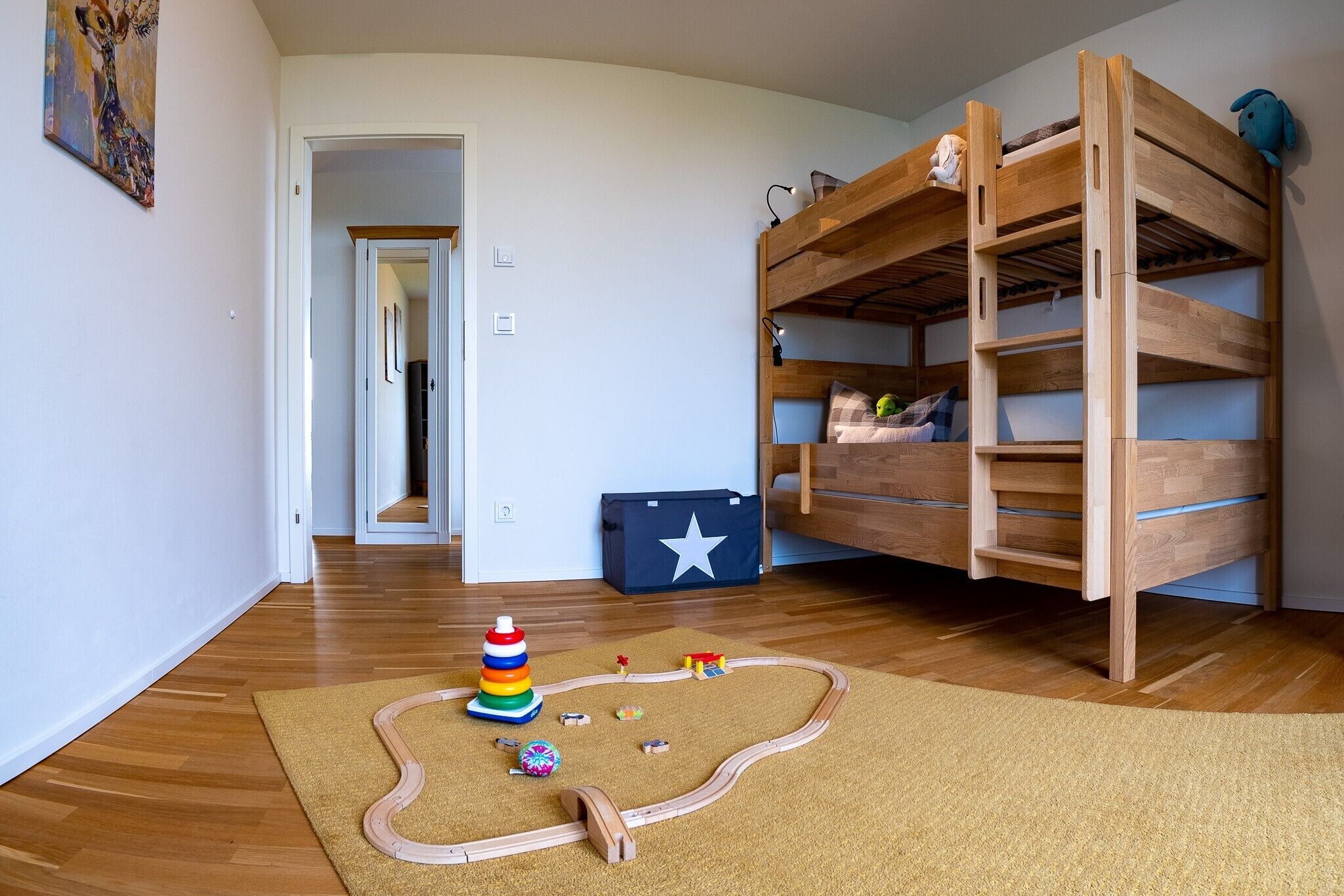 A room with a bunk bed, a play area with toys, and a star-patterned bag.