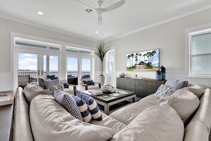 A spacious living room with a large sofa, a coffee table, and a painting on the wall.