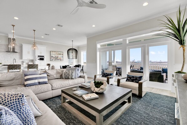 A spacious living room with a large sofa, coffee table, and a view of the city through large windows.