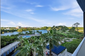A view of a lake with a pool, palm trees, and a bridge.