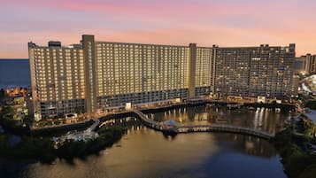 Un gran hotel con varias torres altas, un patio central y una masa de agua que refleja los edificios.