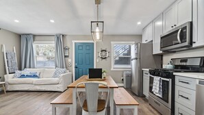 A modern kitchen with white cabinets, a stainless steel refrigerator, and a microwave.