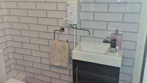 A bathroom with a white sink, a soap dispenser, and a towel rack. - Newport Cozy Apartment Retreat (Newport)