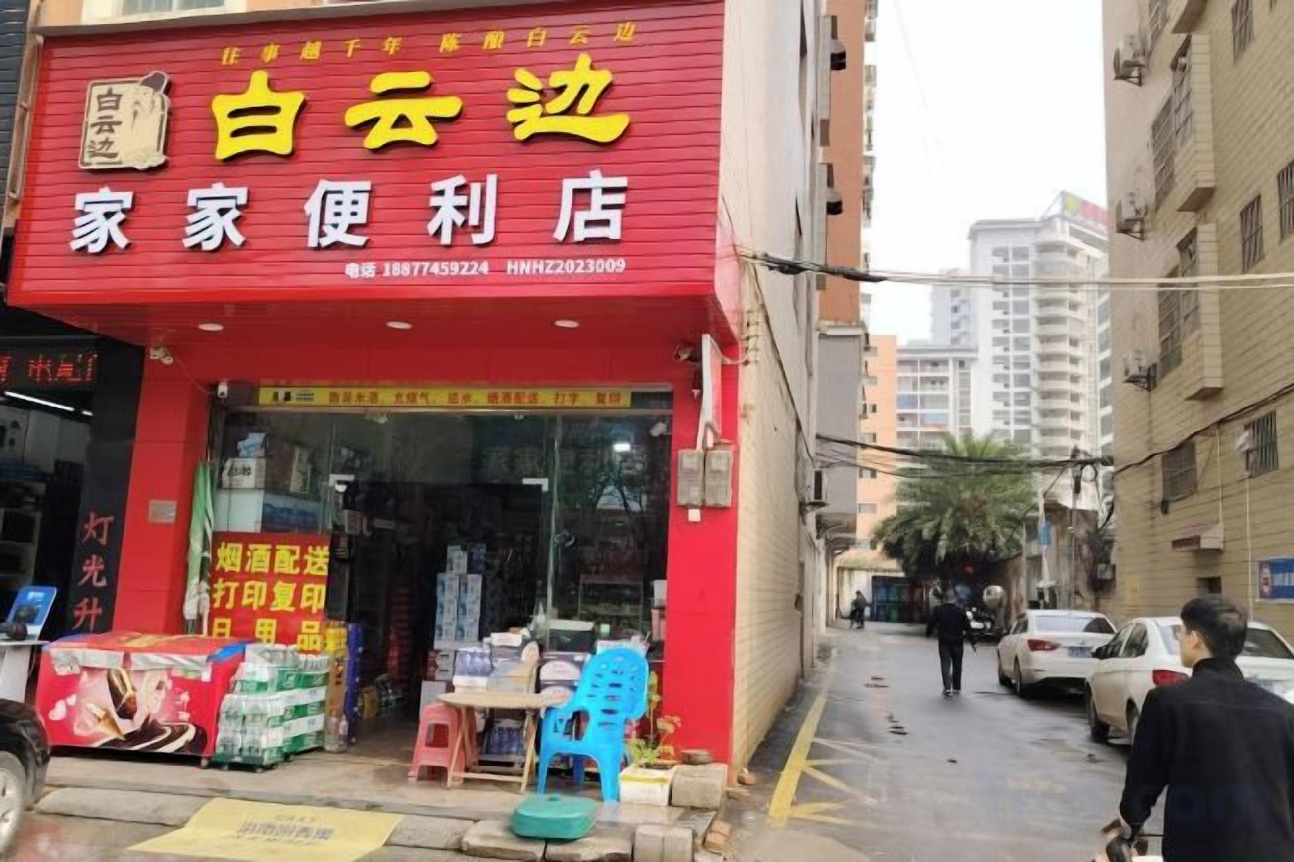 A storefront with a red sign, outdoor seating, and a pedestrian walkway.