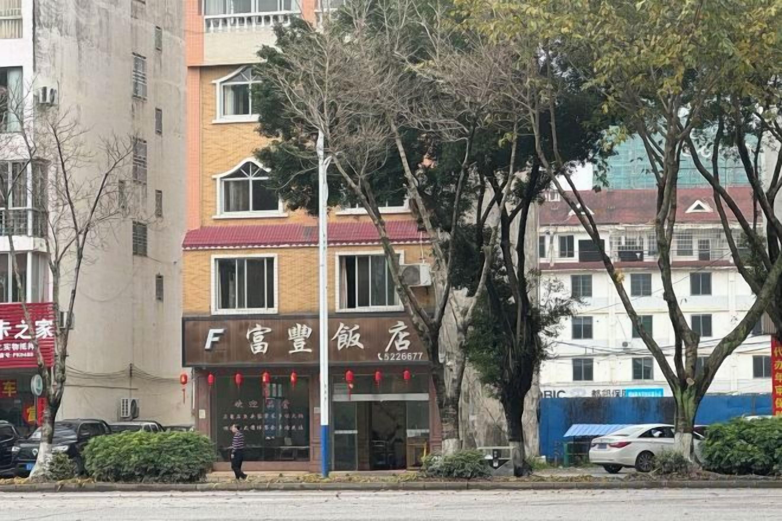 Un edificio con escaparate que dice 'F Wealthy Hotel' y una persona caminando adelante.