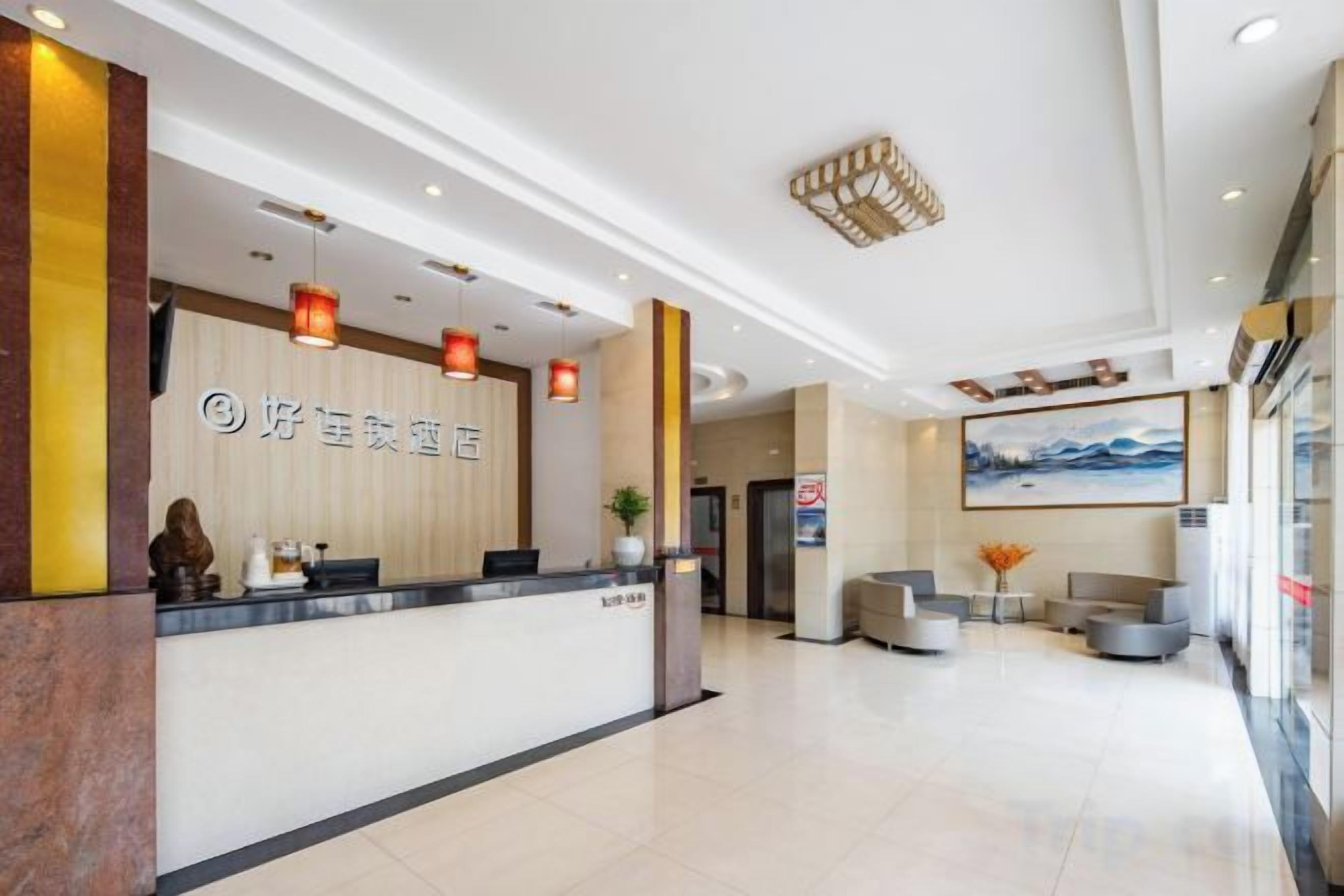 A hotel reception area with a reception desk, seating area, and a painting on the wall.