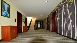 A hotel hallway with a striped carpet, wooden doors, and a staircase leading to another floor. - 3 Good Chain Hotels (Hezhou College Branch) (Hezhou)