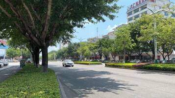 Une rue bordée d’arbres, avec des immeubles et des voitures garées.