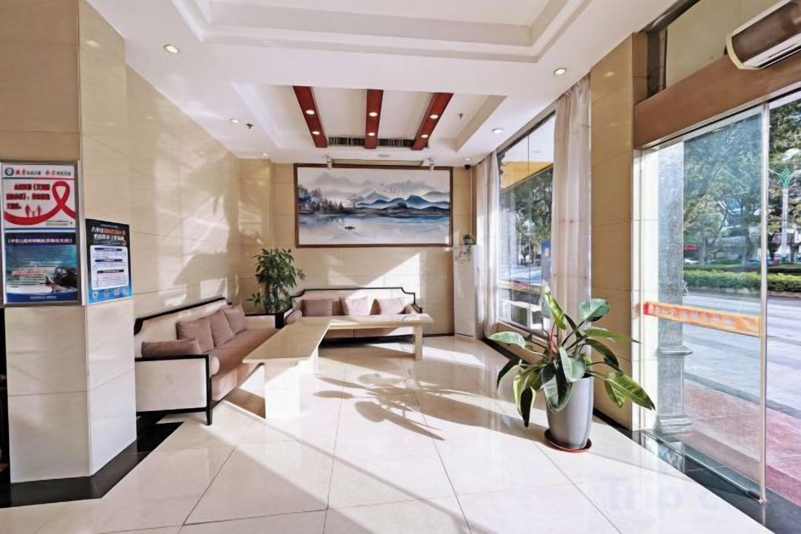 Un vestíbulo de hotel con mostrador de recepción, zona de estar y grandes ventanales que ofrecen vistas al exterior.