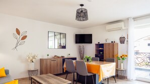 Una sala de estar moderna con comedor, televisor de pantalla plana y un ventanal con balcón.