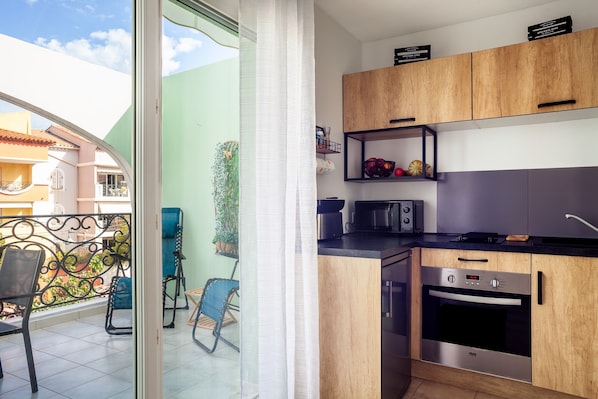 A modern kitchen with wooden cabinets, a built-in oven, and a microwave.