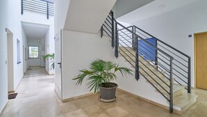 Ein modernes Interieur mit Treppe, einer Topfpflanze und einem Flur, der in ein weiteres Zimmer führt.