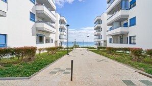 Ein Weg zu einem Gebäude mit Balkonen, wolkenlosem Himmel und Blick aufs Meer.