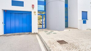 Ein Gebäudeeingang mit blauer Tür, Brandmelder und einer großen zylindrischen Struktur.