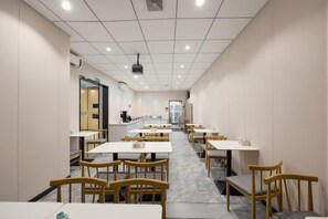A long dining area with tables and chairs, a counter, and a view of the kitchen. - Mingji Hotel (Nansha Hotel, Guangzhou) (Guangzhou)