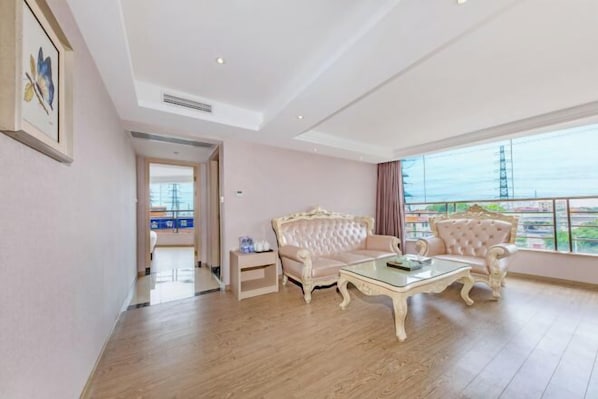 A spacious room with a large window, a sofa, a coffee table, and a small side table. - Mingji Hotel (Nansha Hotel, Guangzhou) (Guangzhou)