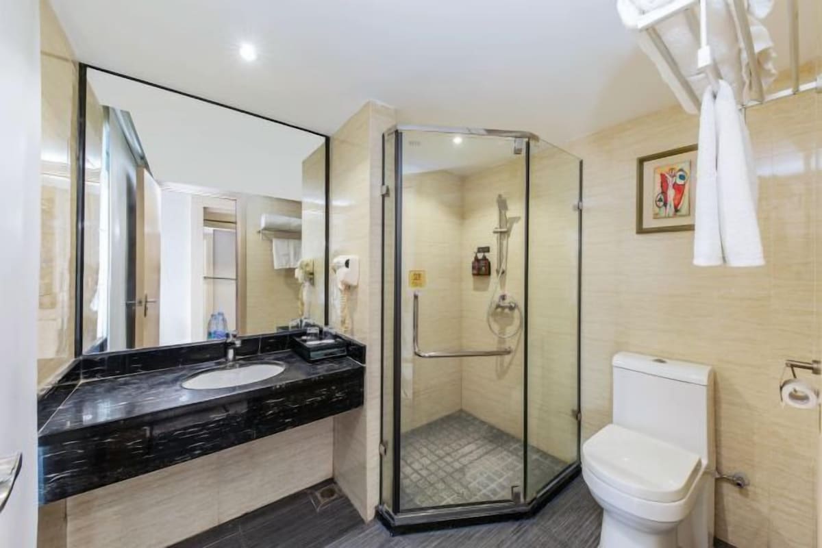 A modern bathroom with a glass-enclosed shower, a white toilet, and a black marble sink.