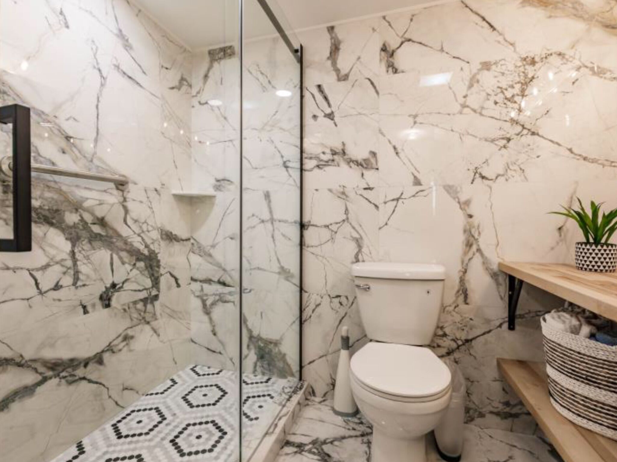 A bathroom with a toilet, a shower area, and a patterned floor.