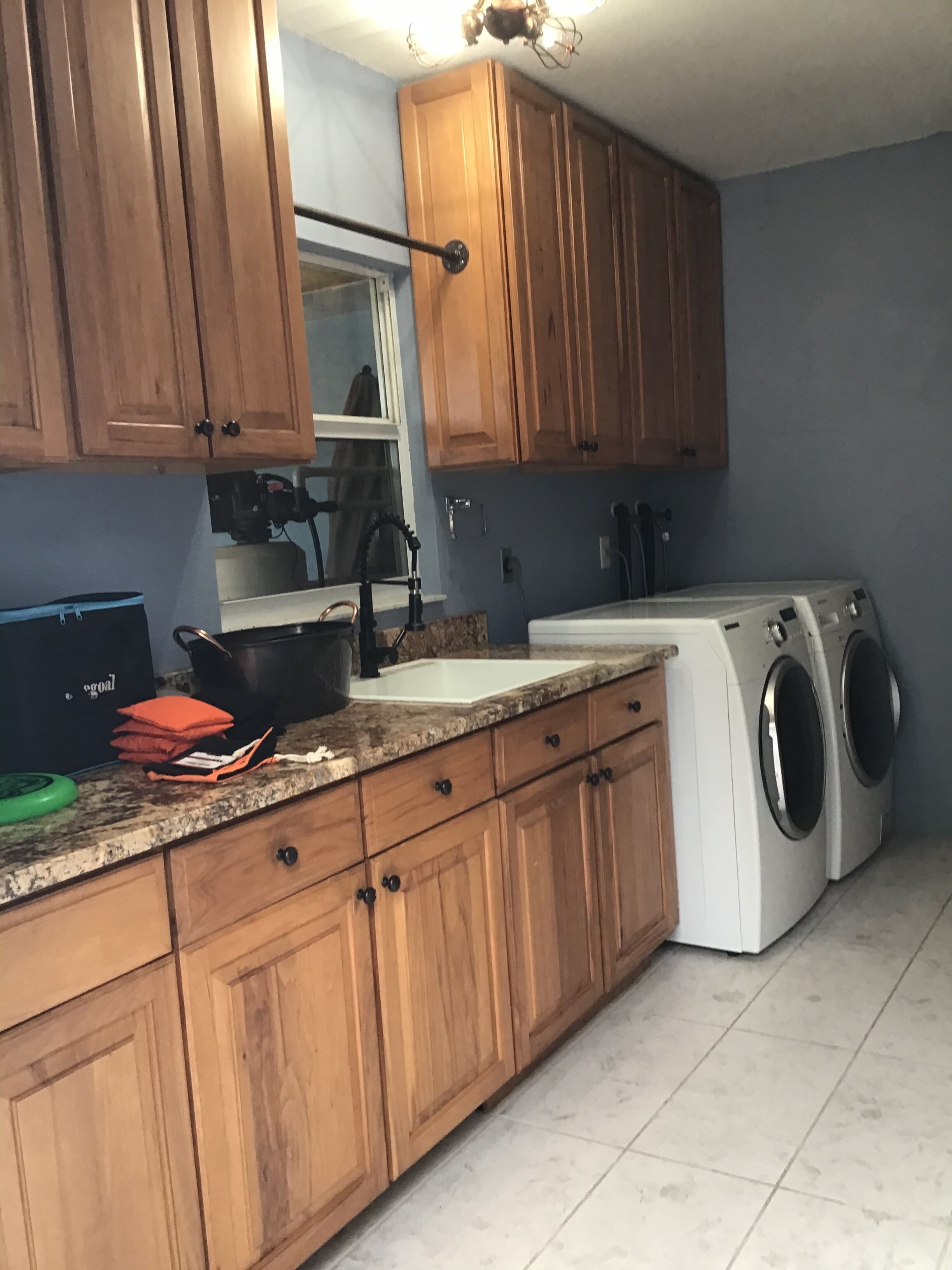 Une cuisine avec des meubles de rangement en bois, un évier, une cuisinière et un lave-linge.