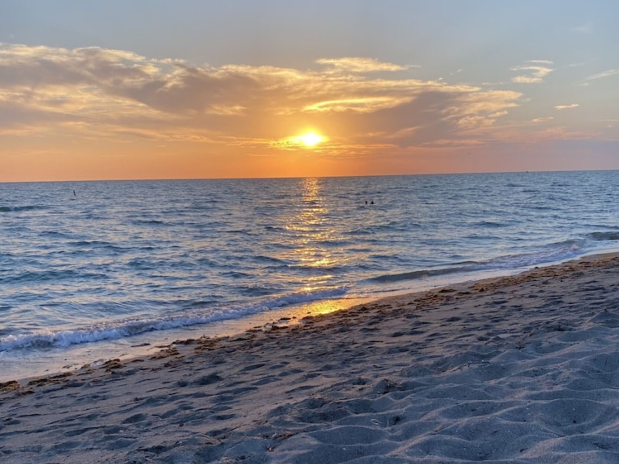 A beach with a sunset over the ocean.