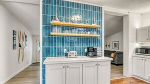 Cozinha moderna com armários brancos, painel de fundo azul e bancada de madeira.