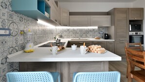 A modern kitchen with a central island, wooden cabinets, and patterned backsplash. - Holiday Apartment 'Dolcecasa' with Mountain View, Private Terrace & Wi-Fi (Dorgali)