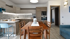 A modern kitchen with wooden cabinets, a central island, and a dining area with chairs. - Holiday Apartment 'Dolcecasa' with Mountain View, Private Terrace & Wi-Fi (Dorgali)
