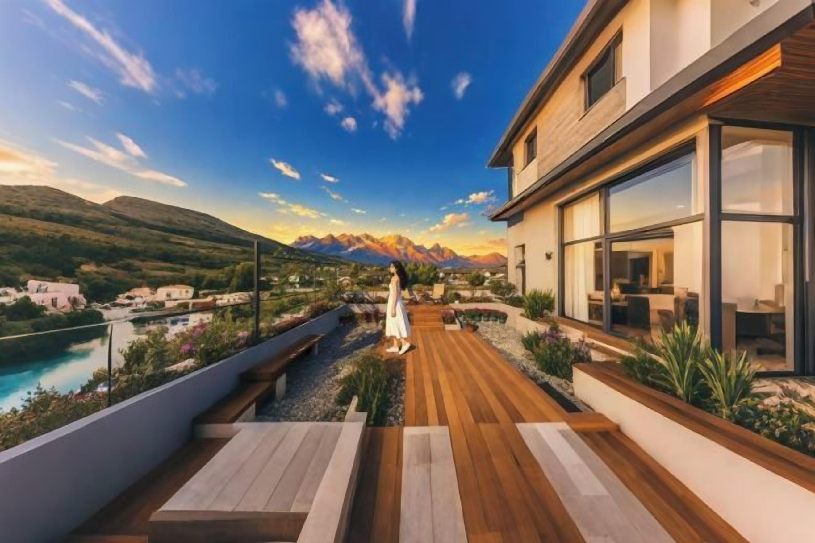 A modern building with a wooden deck, a pool, and mountains in the background.