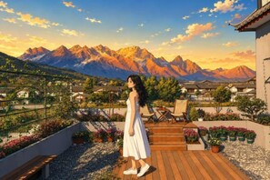 Una mujer en una cubierta de madera con vistas a un paisaje montañoso y edificios tradicionales.