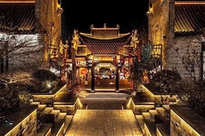 A traditional building with a central entrance, steps leading up to it, and a tiled roof.
