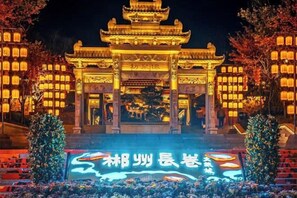 A traditional Chinese building with a prominent entrance and illuminated lanterns. - Guoguang Hotel (Yizhang)
