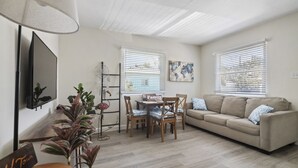 En stue med sofa, spisebord, stole, fjernsyn og lampe.