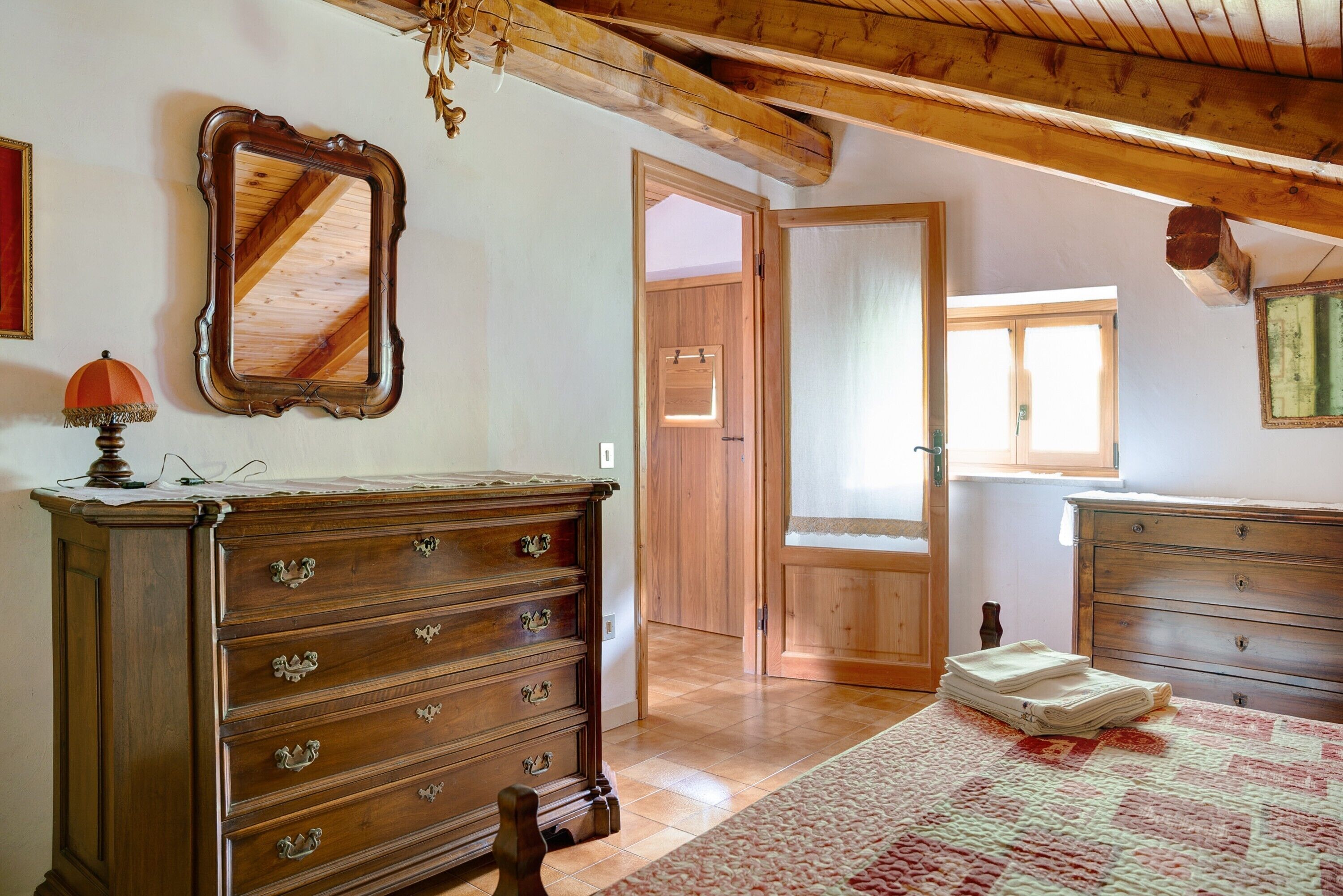 Quarto com penteadeira de madeira, espelho e porta que dá para outro cômodo.