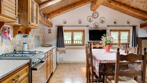 Eine Küche mit Holzausstattung, einem Herd und einem Essbereich mit Tisch und Stühlen.