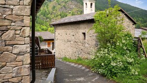 Ein Steinhaus mit einem Glockenturm, einem gepflasterten Weg und üppigem Grün.