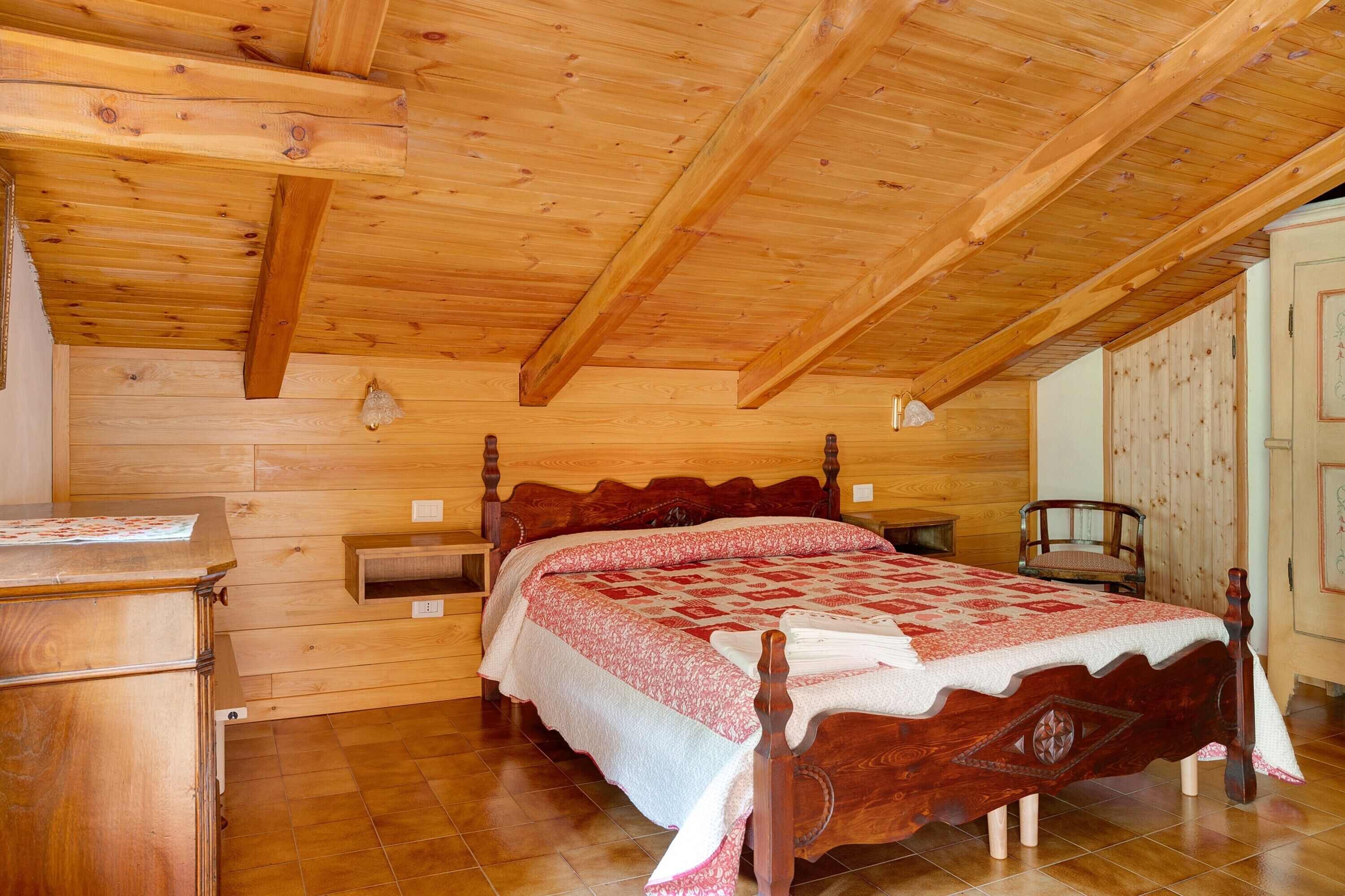 Ein Schlafzimmer aus Holz mit Bett, Holzwänden und geneigter Decke.